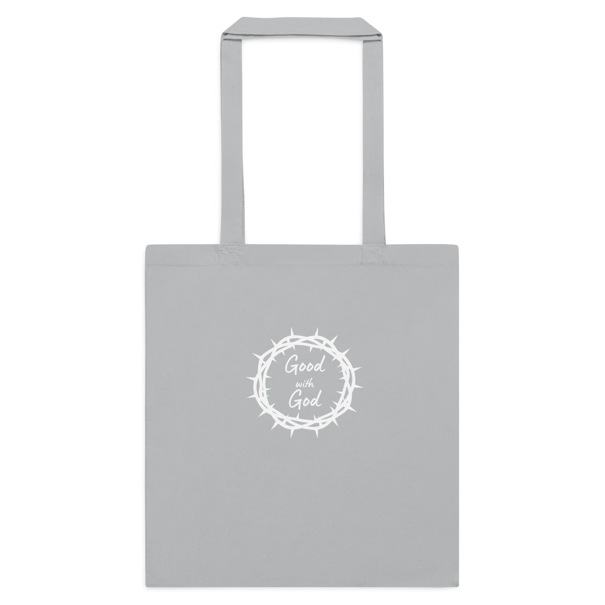 A light gray canvas tote bag with two handles, featuring a white circular graphic in the center with a crown of thorns and the words 'Good with God' written inside.