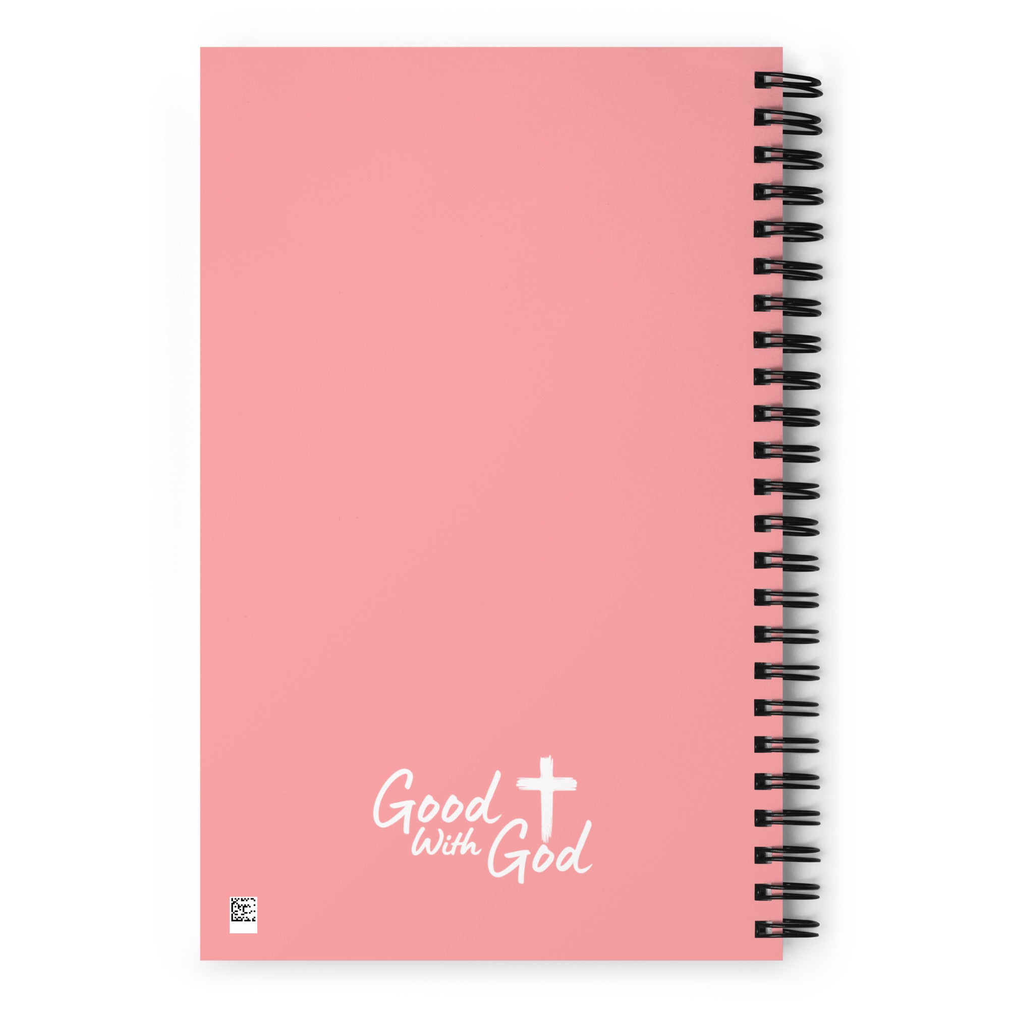 A pink spiral notebook with a black wire coil binding and the words 'Good with God' printed in white near the bottom, alongside a white cross graphic.